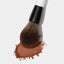 Smaller end of the Makeup By Mario's F2 Dual-Ended Powder Brush dipped in powder bronzer.